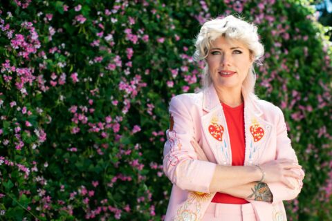 Clementine Ford smiles in front of a hedge.