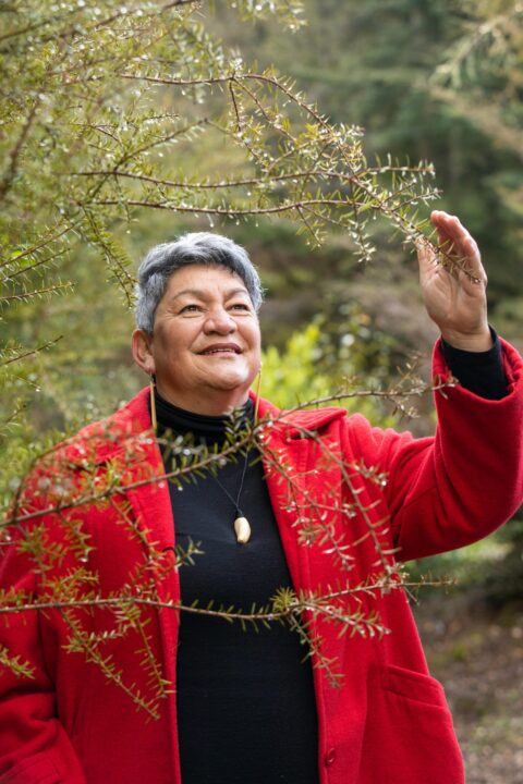 Donna Kerridge standing in garden wearing a red coat and black top