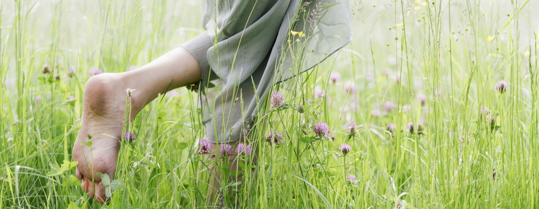 woman with bare feet walking through a green field
